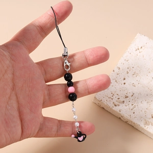 Détail du bijou de téléphone perlé avec breloque théière cœur rose et fermoir argenté