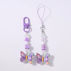 Close-up of purple butterfly beaded phone charms with stars and pearls on white background
