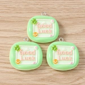 Detail of green square resin charms with Good Luck text and four-leaf clover for DIY jewelry