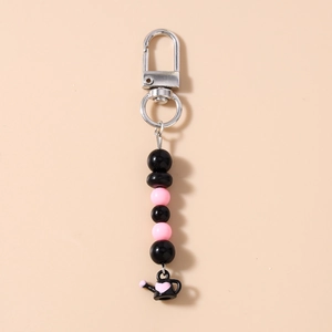 Détail du porte-clés perlé avec perles roses et breloque théière noire à motif de cœur