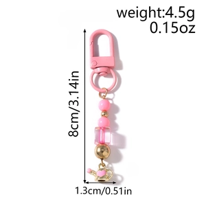 Detailed view of pink beaded keychain with a small golden watering can charm on white back