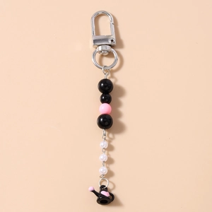 Détail de porte-clés perlé avec breloque théière coeur noir et accents roses sur fond rose