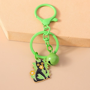Detail of cartoon black cat keychain with green leaves and a matching bell ornament
