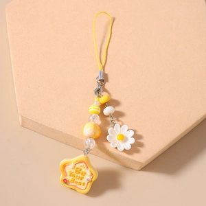 Detailed shot of yellow beaded phone charm with daisy flower and star pendant engraving