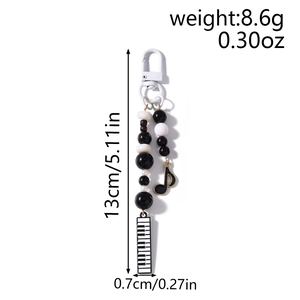 Detail view of music beaded phone strap with piano and note charms, 13cm length
