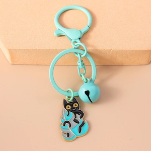 Detail of cartoon black cat keychain with mint green bell and enamel leaf charm