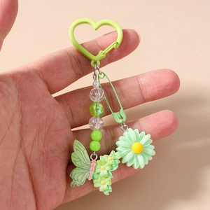 Détail du porte-clés perlé avec marguerite verte, papillon et fermoir en forme de cœur