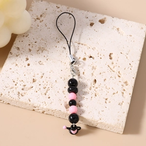 Détail du bijou de téléphone perlé avec perles noires et roses et pendentif théière cœur