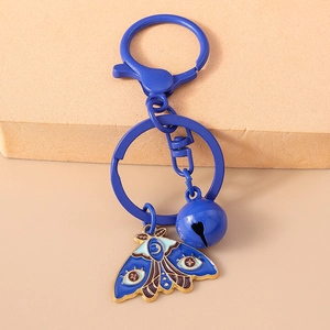 Detail of blue moth keychain with enamel moon and eye patterns and a small golden bell