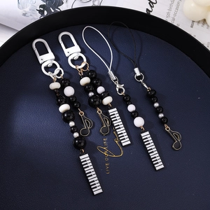Detailed view of black and white musical bead charms with piano and note pendants