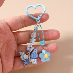 Détail du porte-clés perlé avec breloque papillon bleu et fleur sur une épingle de sûreté