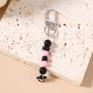 Détail macro du porte-clés à perles noir et rose avec personnage mignon sur pierre