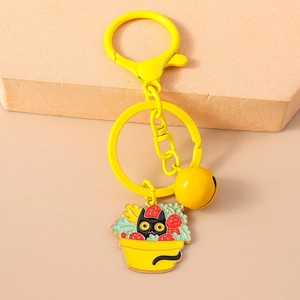 Detail of yellow cat keychain with strawberry plant enamel charm and small metal bell