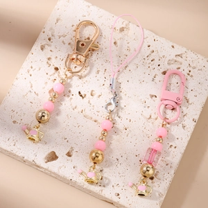 Detail of pink beaded phone charm and keychain with a golden kettle charm and lobster clasp