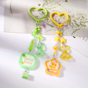 Détail de porte-clés perlés avec ours et citations inspirantes en vert et jaune