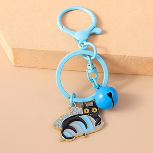 Detail of light blue cartoon cat keychain with metal bell and golden enamel finish