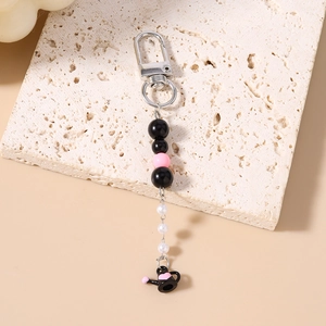 Gros plan du pendentif théière noire et de la dragonne perlée en noir rose et blanc