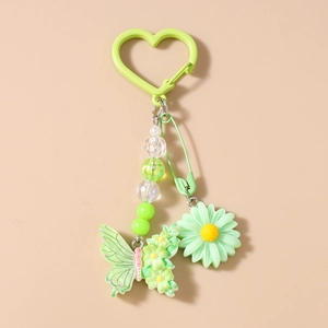 Détail d'un porte-clés vert avec fleur de marguerite, papillon en résine et perles