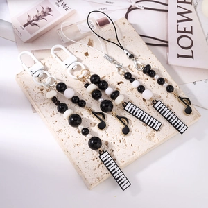 Beaded music phone charms with piano key and note pendants on marble display