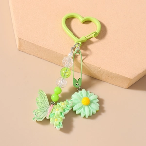 Détail d'un porte-clés papillon vert et marguerite avec clip en forme de cœur sur socle