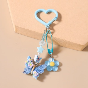 Détail d'un porte-clés bleu avec papillon et perles étoilées sur un support géométrique