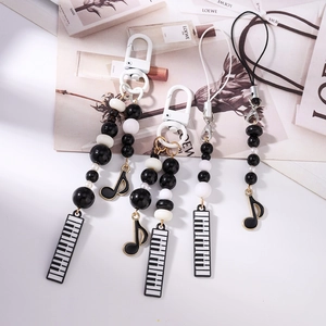 Detail of beaded mobile straps with piano and music note charms in black and white