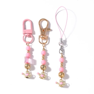 Pink beaded phone charms with heart teapot pendants on white background for keys