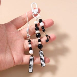 Detail of beaded phone strap with black and white music notes and piano key charms