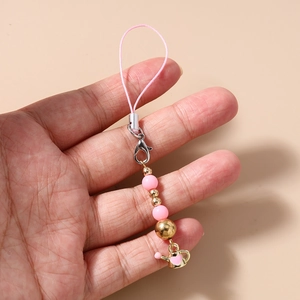 Detailed view of pink beaded phone charm featuring a gold kettle pendant with heart