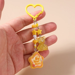 Détail d'un porte-clés ours et étoile jaune avec breloque Be Your Best et crochet