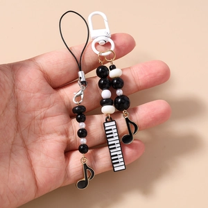 Close-up of music-themed phone charm with piano key and note charms and black white beads