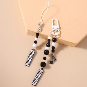 Detailed close-up of music themed phone charms with black and white beads and piano pendants