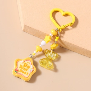 Détail d'un porte-clés jaune avec cœur, perles, ours à paillettes et breloque étoile