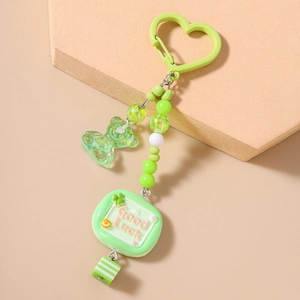 Détail d'un porte-clés vert en forme de cœur avec pendentif ours et perles colorées