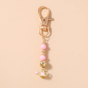 Close-up of pink beaded keychain with a golden miniature watering can heart charm