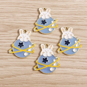 Macro shot of bunny planet charms with gold accents on a natural wood surface