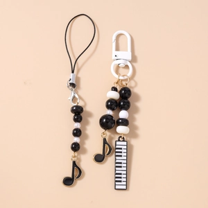 Detailed view of music-themed phone charm and keychain with piano and note charms