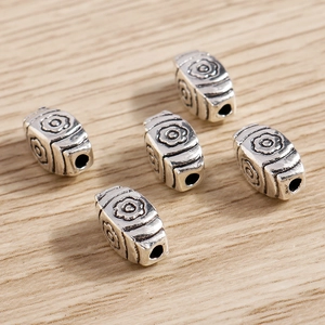 Macro shot of silver vintage flower spacer beads with oxidized details on wooden surface