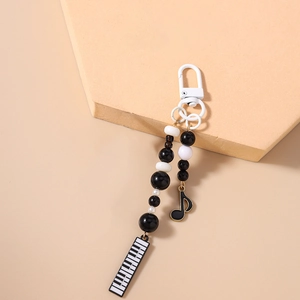 Close-up of piano keyboard and music note charms on black and white beaded keychain