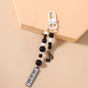 Close-up of black and white beaded phone chain featuring piano and musical note charms