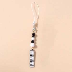 Close-up of black and white beads with a piano key charm on a minimalist phone lanyard