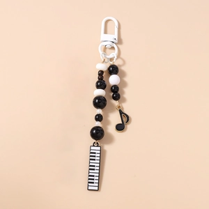 Detail of music-themed phone charm with piano keyboard and black white beads