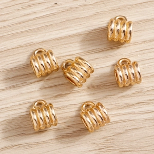 Macro detail of six gold plated textured cylinder beads with rings for DIY jewelry making