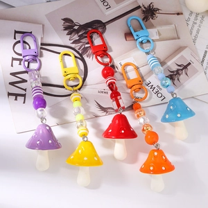 Five colorful mushroom keychains with striped beads and metal clasps in a stylish row