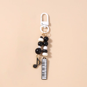 Close-up of music-themed keychain featuring black and white beads with piano and note charms