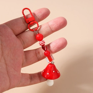 Detail of red beaded mushroom keychain with lobster clasp held in hand for scale