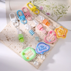 Detail of beaded keychains with striped pearls and positive message pendants