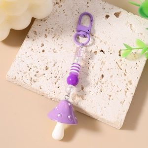 Detail of purple mushroom keychain with striped beads and lobster clasp on stone