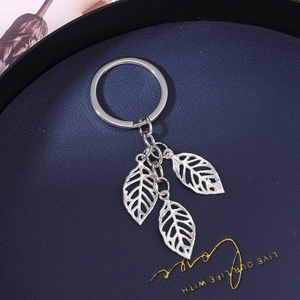 Detailed view of silver hollow leaf charms on a metal keychain with polished finish