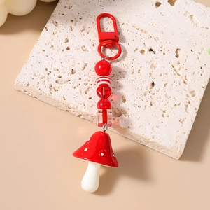 Close-up of red and white mushroom pendant with striped beads on stone texture